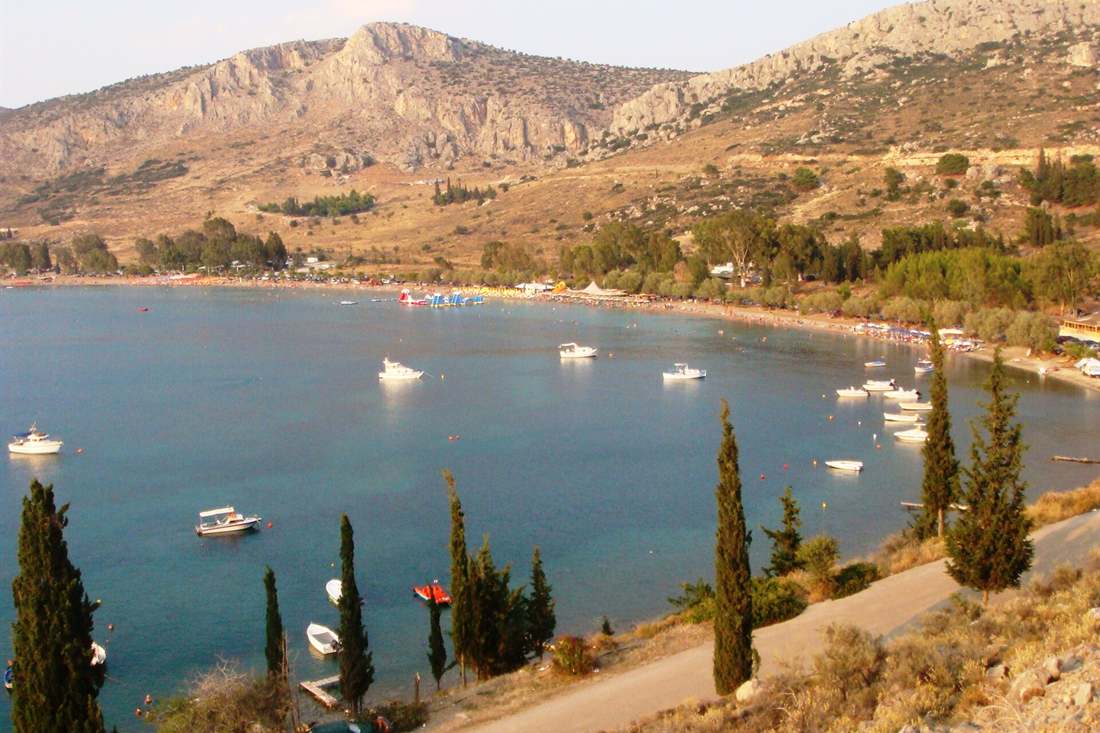 Karathona bay near Nafplio with small boats on calm water and a path along the hillside