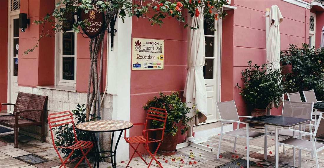 A pink neoclassical house with bougainvillea and cafe tables in the old town of Nafplio