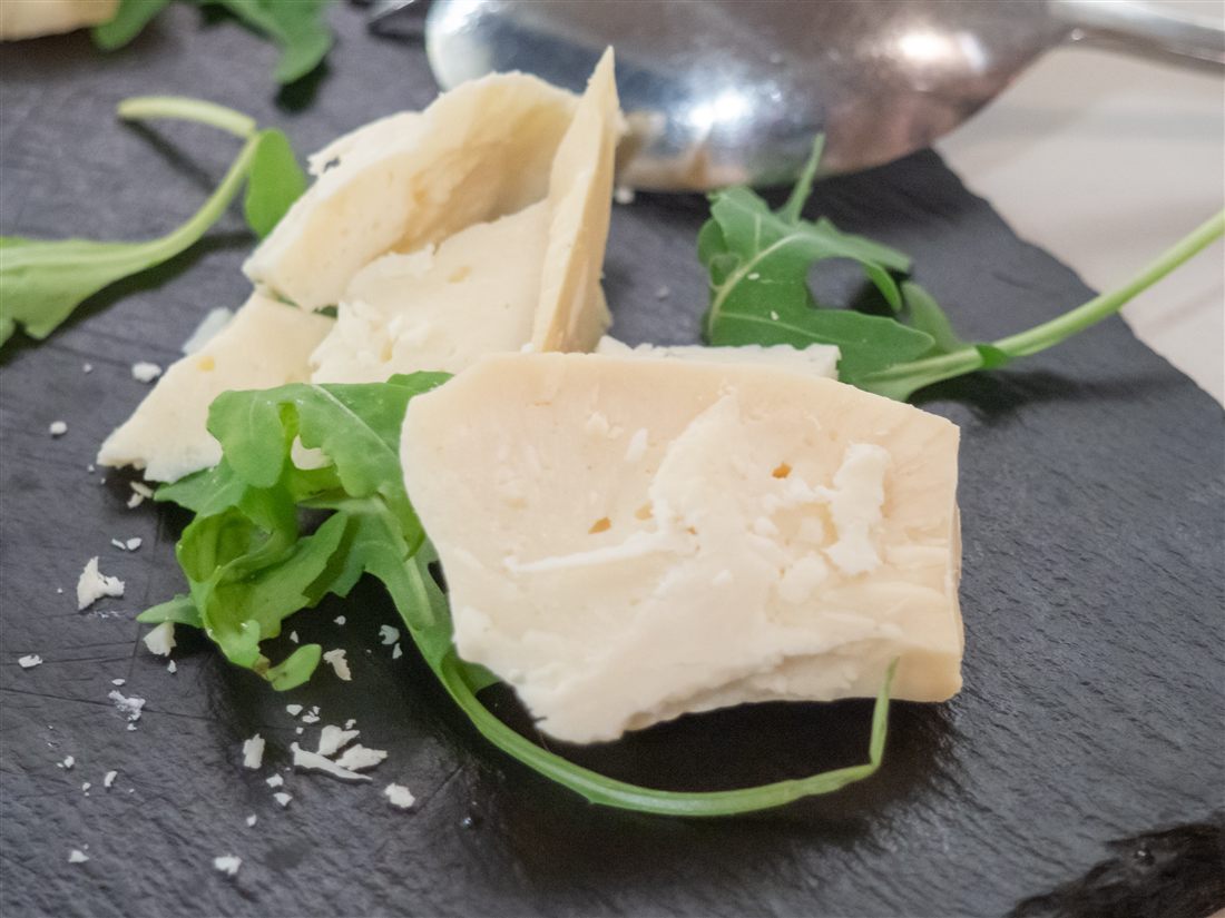 Slices of arseniko, the aged sheep and goat cheese of Naxos, served on slate with rocket at a Naxos cheese tasting.