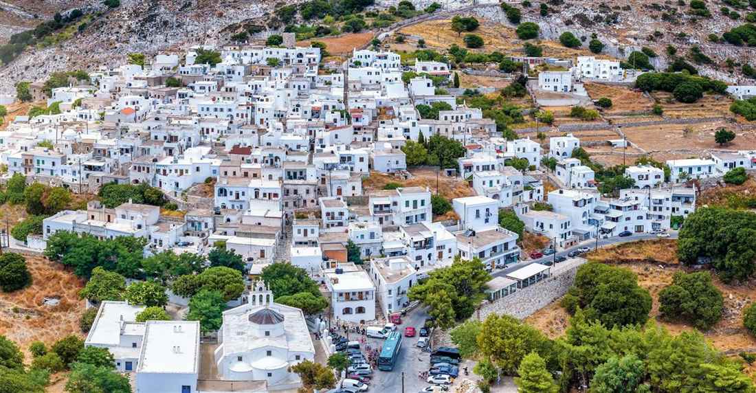 White houses of a Naxos mountain village spread across a hillside above a domed church