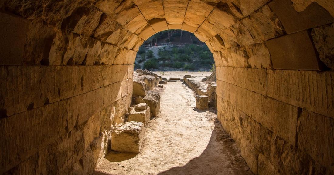 The vaulted stone tunnel that led athletes into the ancient stadium of Nemea, with daylight at the far end.