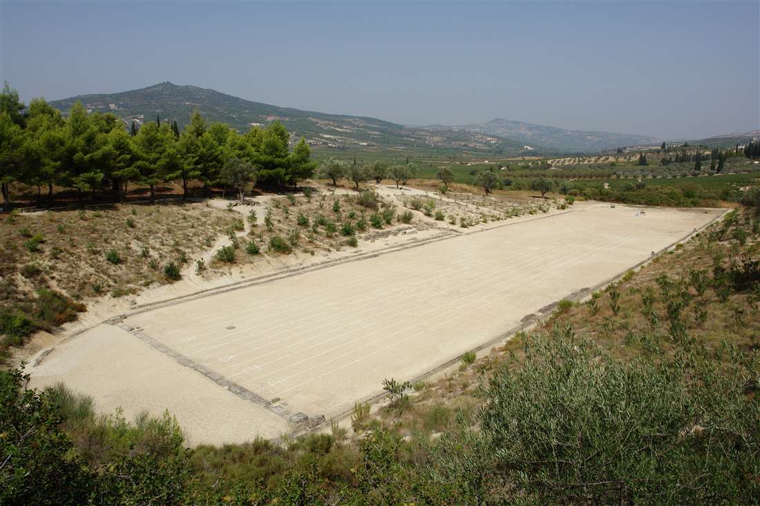 The long running track of the ancient stadium of Nemea among pine trees, explained by the archaeologist on a Nemea guided tour.