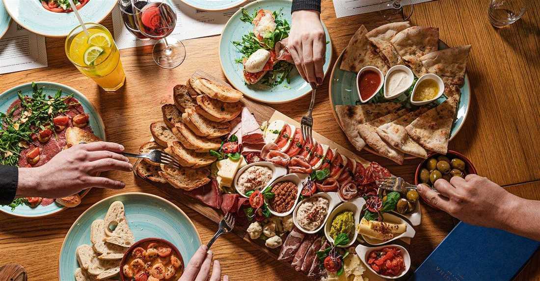 A table of Greek meze plates, bread, cheese, olives and dips shared by diners