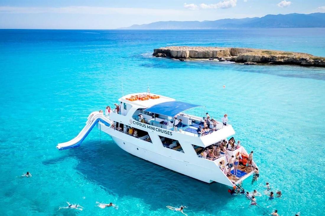 A cruise boat with a water slide anchored in the turquoise Blue Lagoon off the Akamas peninsula