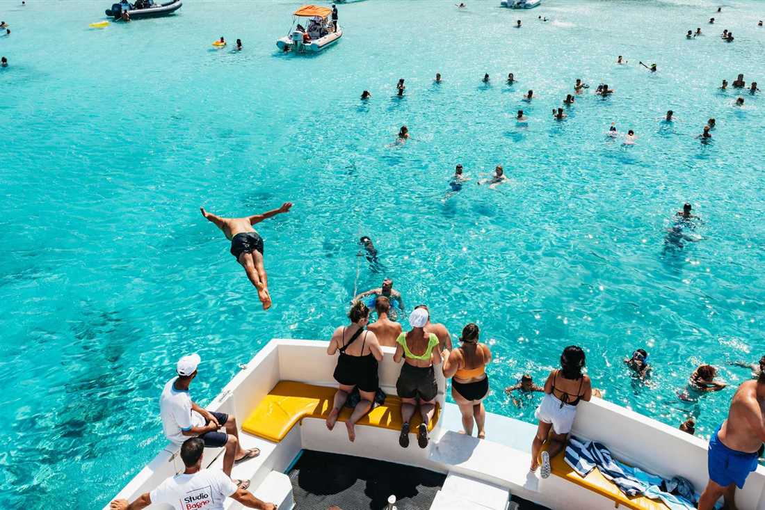 Swimmers dive from a boat into the clear turquoise water of the Blue Lagoon on the Akamas coast