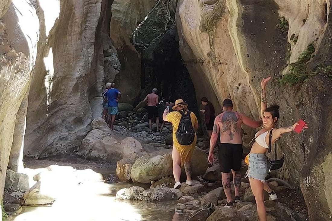 Visitors walk between the high limestone walls of the Avakas Gorge on an Akamas jeep safari