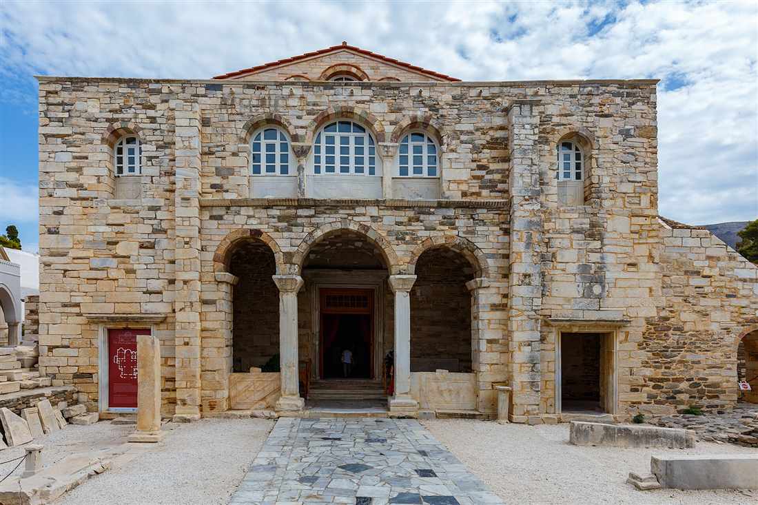 The stone facade and arched porch of the Panagia Ekatontapiliani church in Parikia, the first stop on a Paros bus tour.