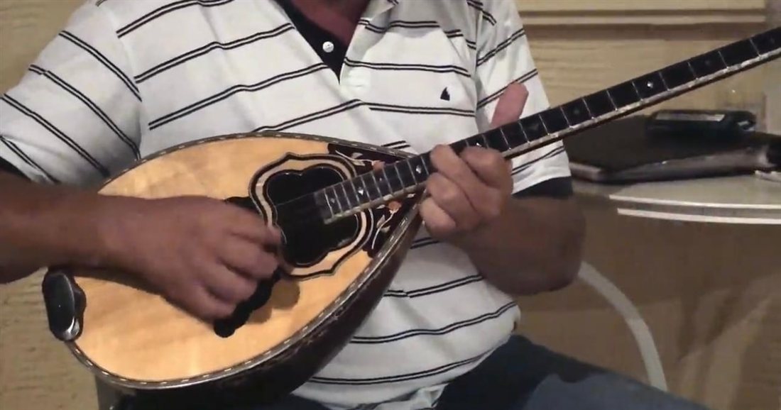 A musician playing a bouzouki, the long-necked Greek lute heard at a Paros Greek night.