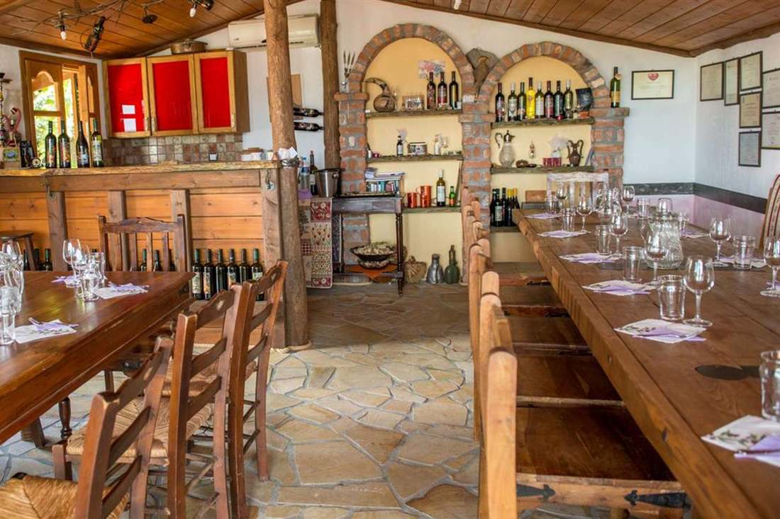 Long wooden tables set with wine glasses in a tasting room lined with shelves of wine bottles