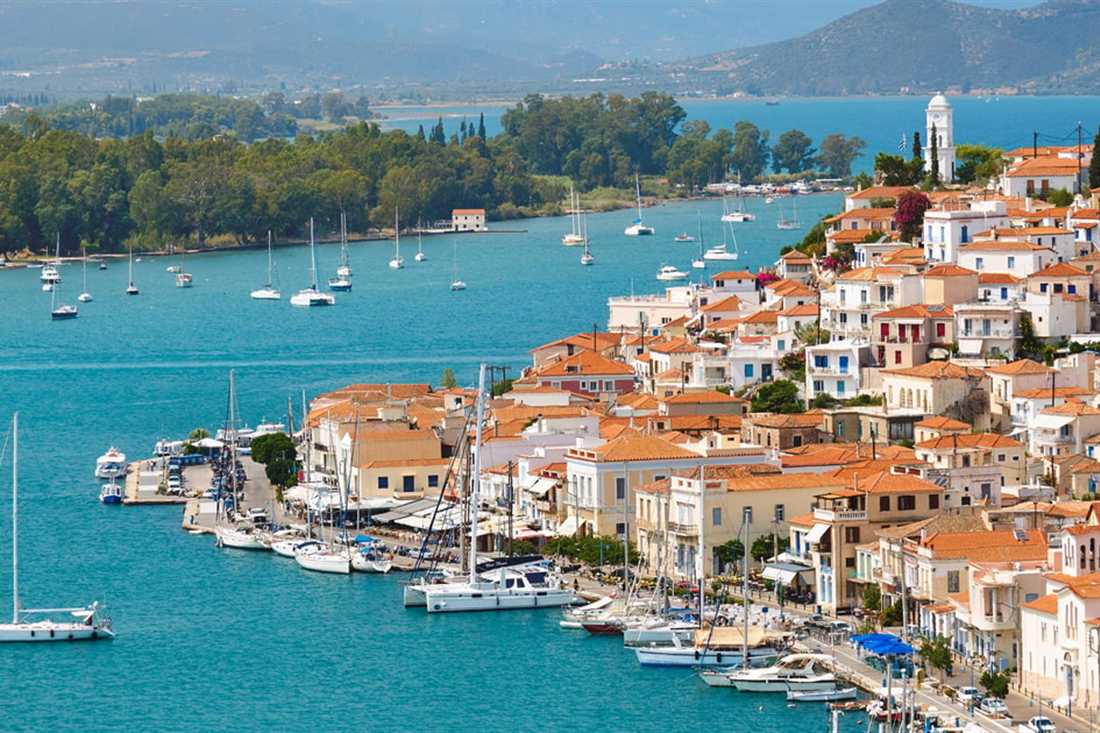 Poros town rising up a hill above its harbour, with red-roofed houses, sailing boats and the strait beyond.