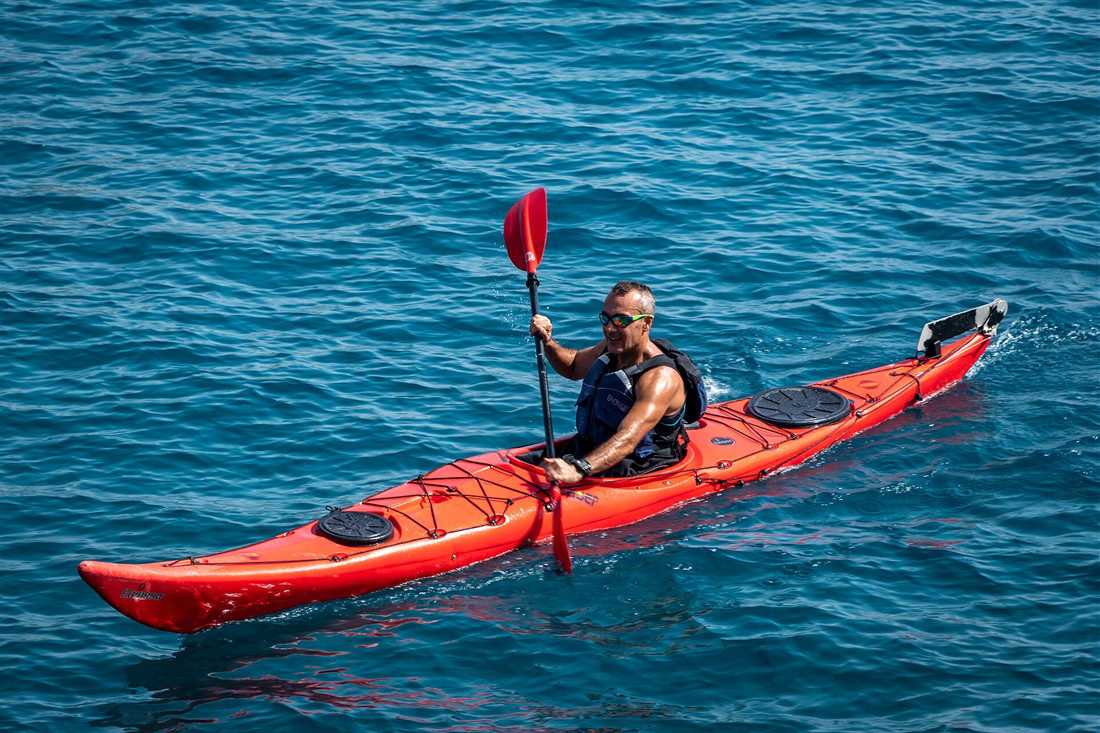 A paddler in a red sea kayak on deep blue water
