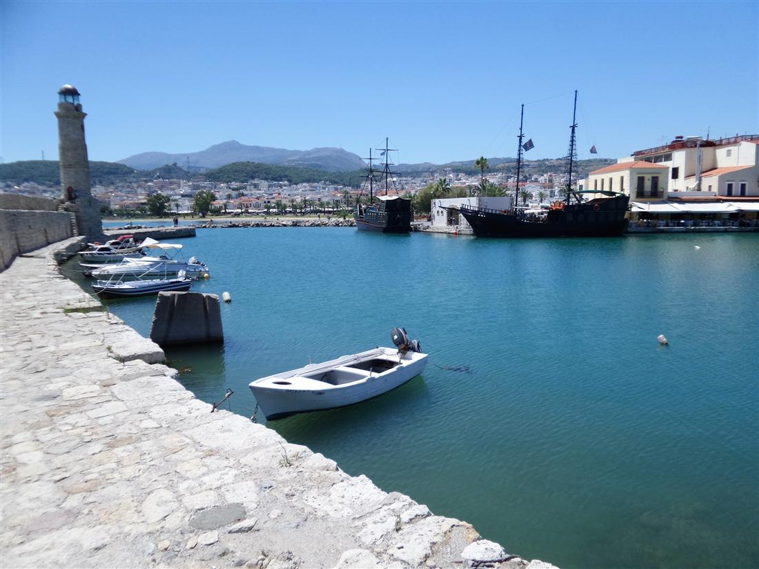 Boats in the old Venetian harbour of Rethymno with the lighthouse at the end of the breakwater, the heart of a Rethymno day trip from Heraklion.