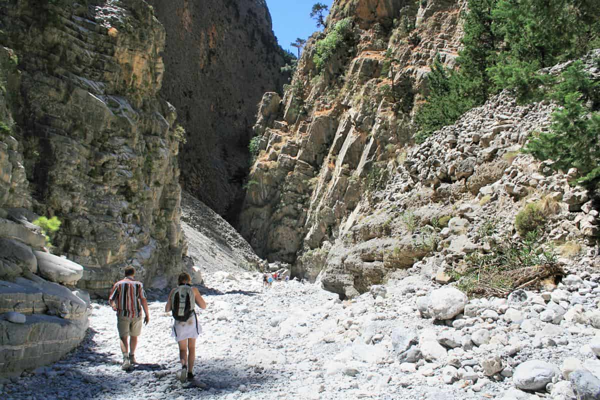 Hikers walking between the rock walls of the Samaria gorge on a Samaria gorge day trip from Heraklion