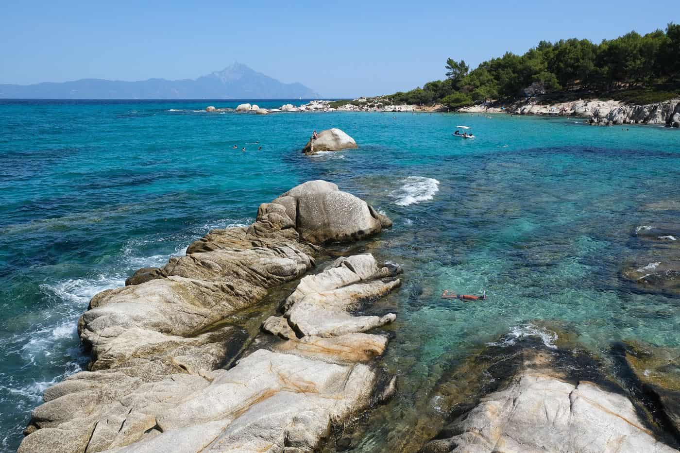 Sithonia tours on the granite rocks and turquoise coves of Kavourotrypes with Mount Athos on the horizon