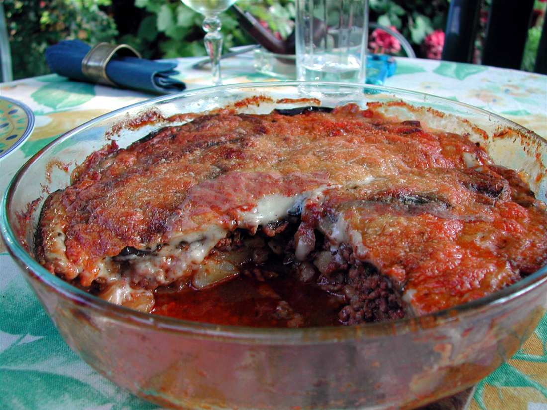 A home-baked moussaka in a glass dish, layered aubergine and minced meat under a golden top, a Greek oven dish cooked in a Skiathos cooking class.