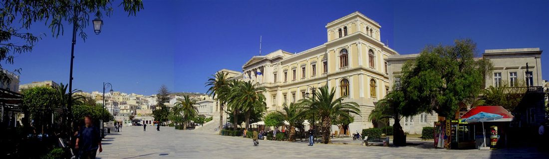 Miaouli Square in Ermoupoli on Syros with the neoclassical Town Hall and palm trees under a blue sky