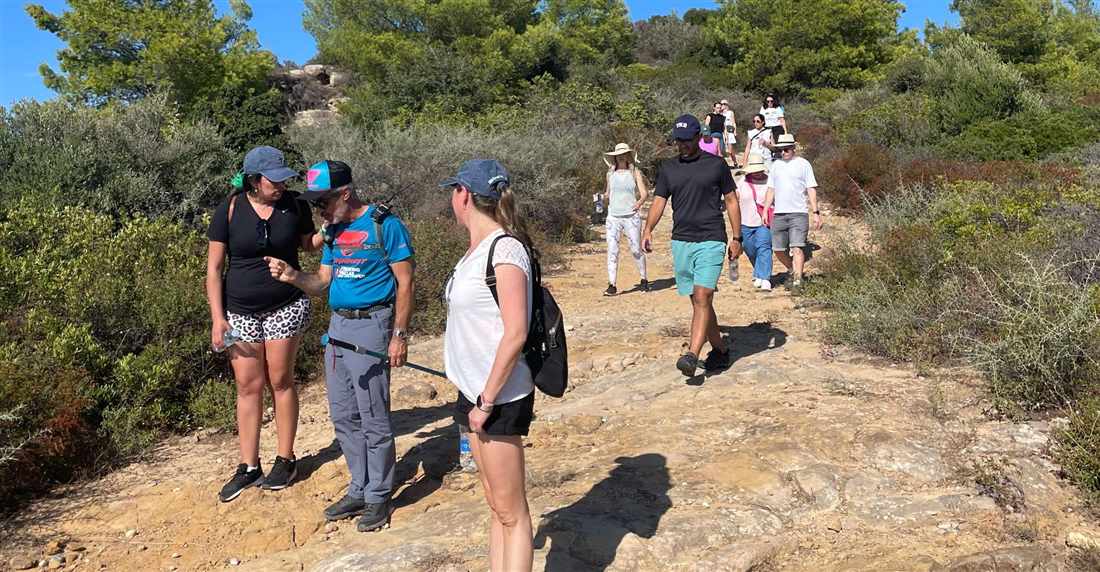 A group of hikers walking a rocky trail through green scrub on Mount Chortiatis above Thessaloniki