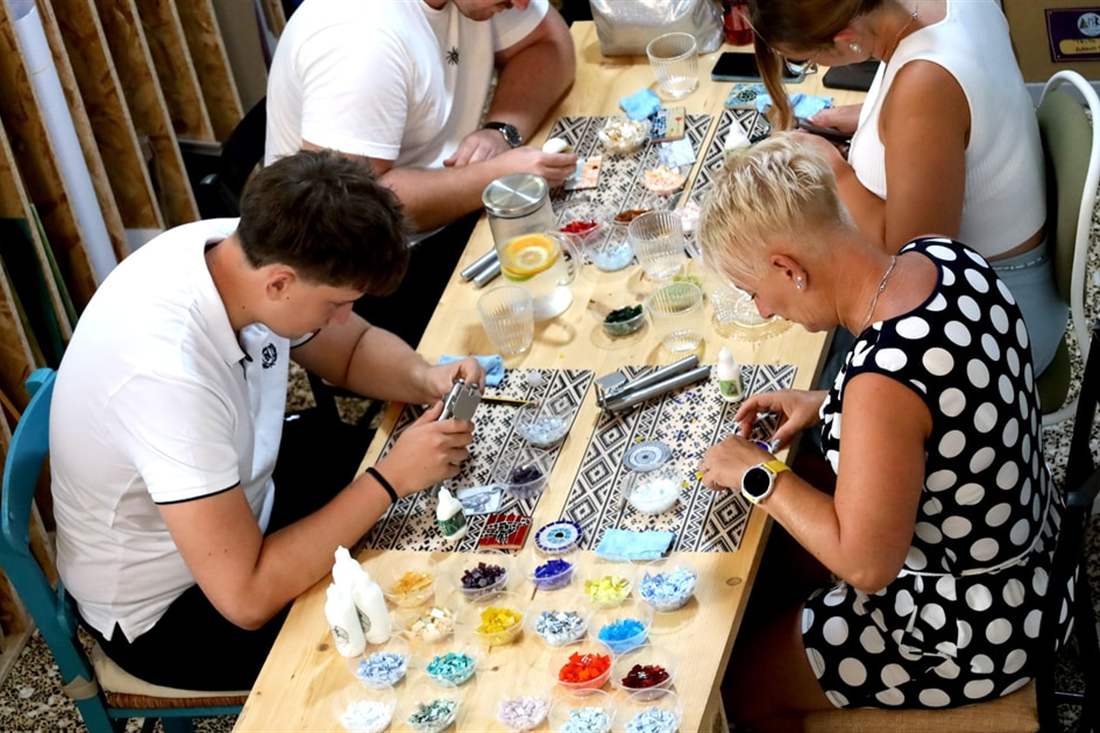 Guests cutting and setting glass pieces at long worktables during a Thessaloniki mosaic workshop.