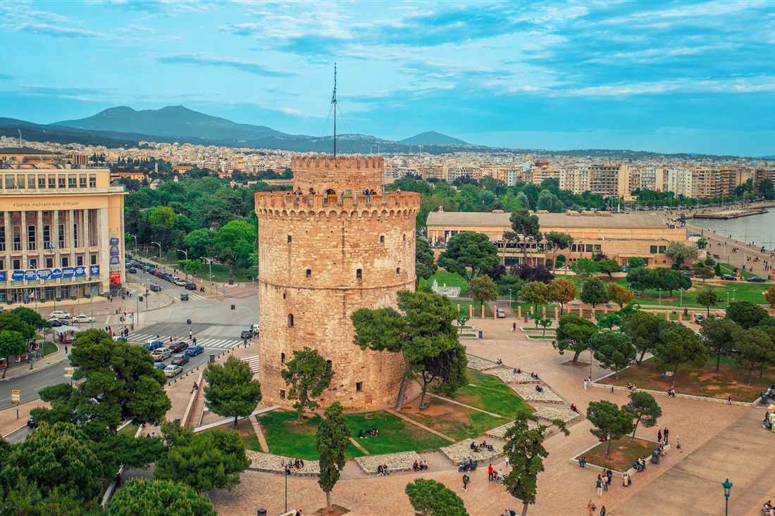 Aerial view of the White Tower of Thessaloniki on the waterfront, with the city, the bay and the hills behind