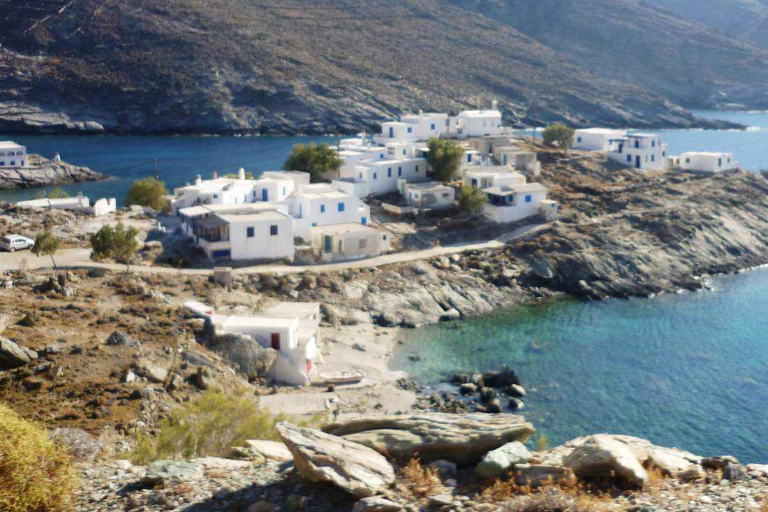 White houses of a small seaside village on Tinos above a turquoise cove