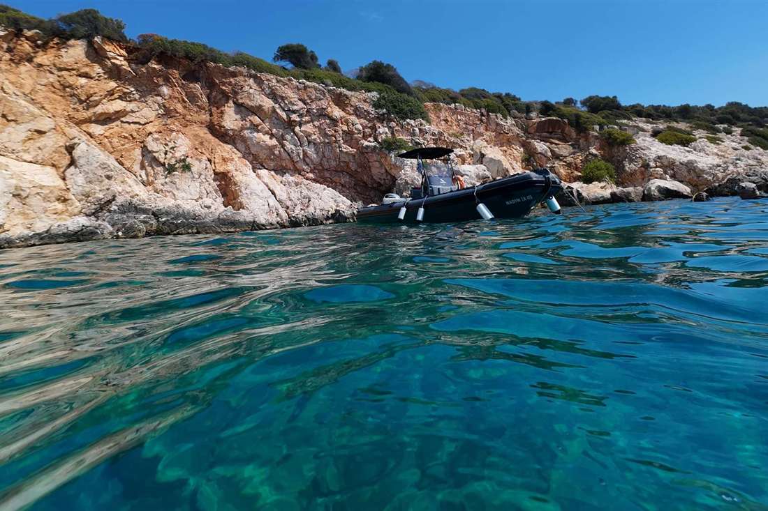 A dive boat moored below a rocky islet in clear turquoise water