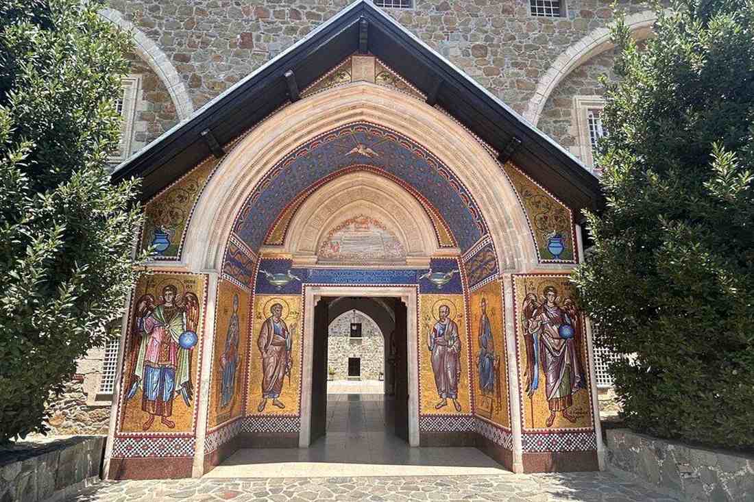 Gold and blue mosaic icons of saints and archangels around the arched stone entrance porch of Kykkos Monastery in the Troodos mountains of Cyprus