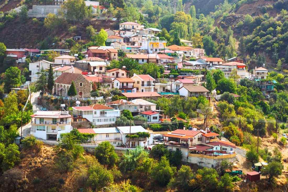A Troodos mountain village of red-roofed houses spread over a green, pine-covered slope