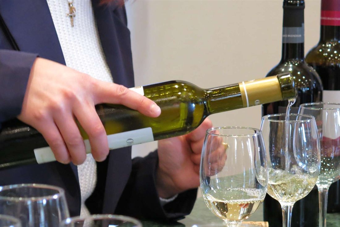 A host pours white Cypriot wine into tasting glasses at a Troodos winery