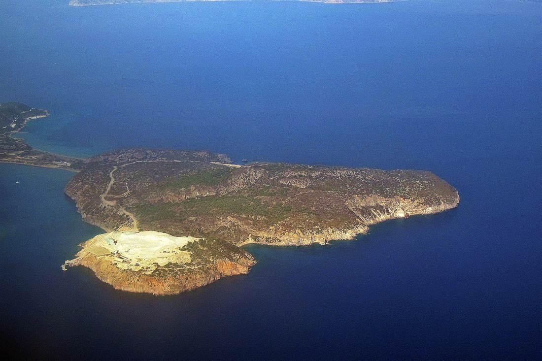 Aerial view of Yali island with a pale quarry area at one end, brown scrub hills and deep blue sea all around