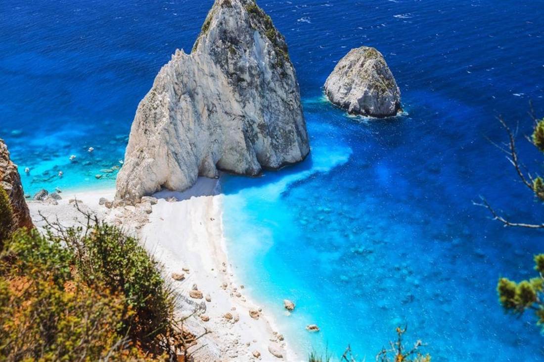 The white Mizithres rocks rising from blue water below the cliffs at Keri, a stop on a Zakynthos e-bike tour.