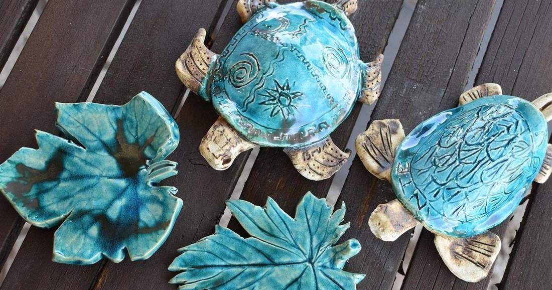 Glazed blue ceramic sea turtles and leaf plates made in a Zakynthos pottery class.