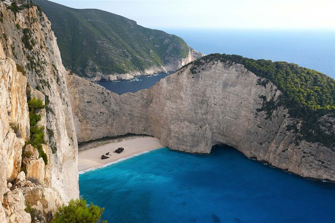 Navagio Beach with the shipwreck on the sand below the white cliffs, the cove a Zakynthos shore excursion reaches by boat or views from above.
